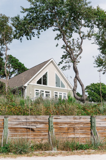 Charming house with large windows at the outdoor wedding venue surrounded by trees and fencing.