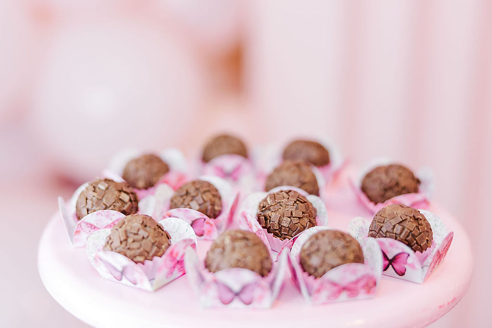 Tray of chocolate brigadeiros in decorative pink wrappers, adding a sweet touch to a first birthday party in Richmond, Virginia.