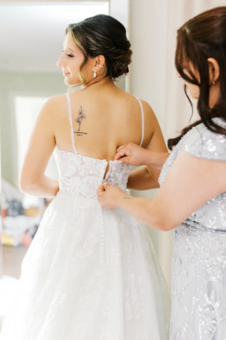 30. Bridesmaid buttoning bride’s wedding dress at Antebellum of New Kent