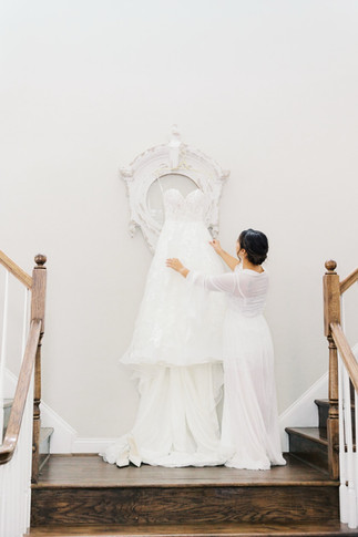 27. Bride holding wedding dress on staircase before Virginia wedding ceremony