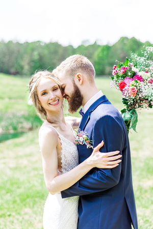 17. Bride holding bouquet with groom smiling beside her