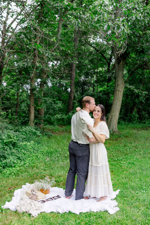 Expecting couple standing close together in a green forest clearing during their gender reveal session in Northern Virginia.