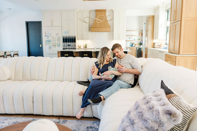 Parents lovingly admiring their newborn baby while sitting on a modern couch in their Richmond, Virginia home.