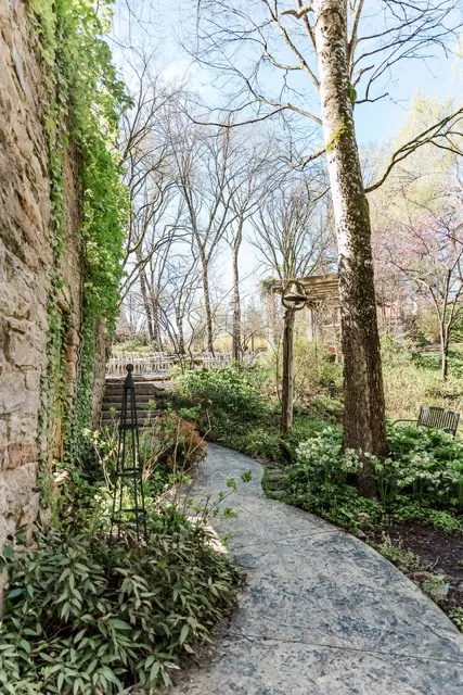	13.	Pathway surrounded by trees and flowering plants at The Mill at Fine Creek, creating a picturesque wedding setting.