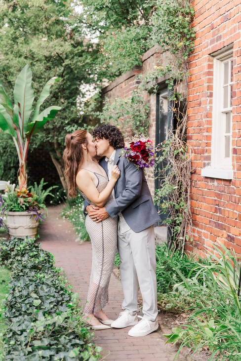 3. Bride and groom posing under a garden arch with lush plants in the background.