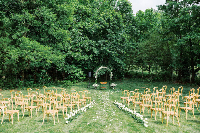 18. Outdoor wedding ceremony aisle with wooden chairs and floral arch at a private residence in Virginia