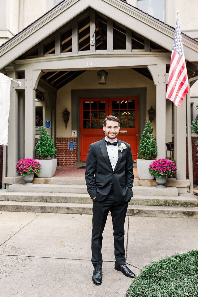 Groom standing outside the wedding venue in Richmond, VA, wearing a black tuxedo and bow tie.