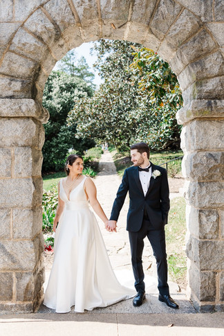 Bride and groom holding hands under a stone archway at a historic wedding venue in Richmond, VA at Maymont Park