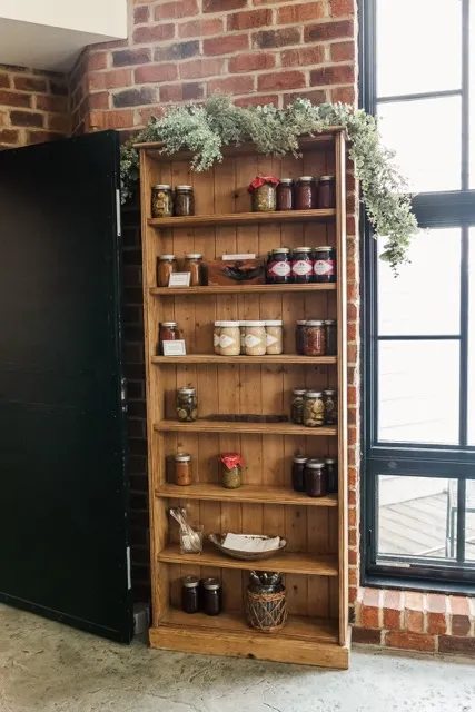 	17.	Wooden shelves stocked with jars and decor in a rustic corner of The Mill at Fine Creek.