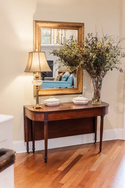 	12.	Classic wooden entry table with a decorative lamp and floral arrangement at The Mill at Fine Creek.