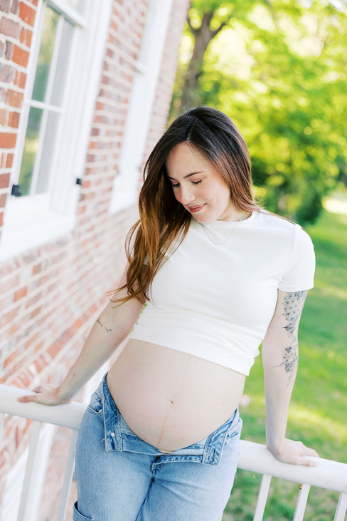 Rebecca holding her baby bump on a porch during Richmond maternity photos