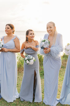 Bridesmaids in various shades of blue dresses stand together, holding elegant white and blue floral bouquets at a Virginia Beach wedding.