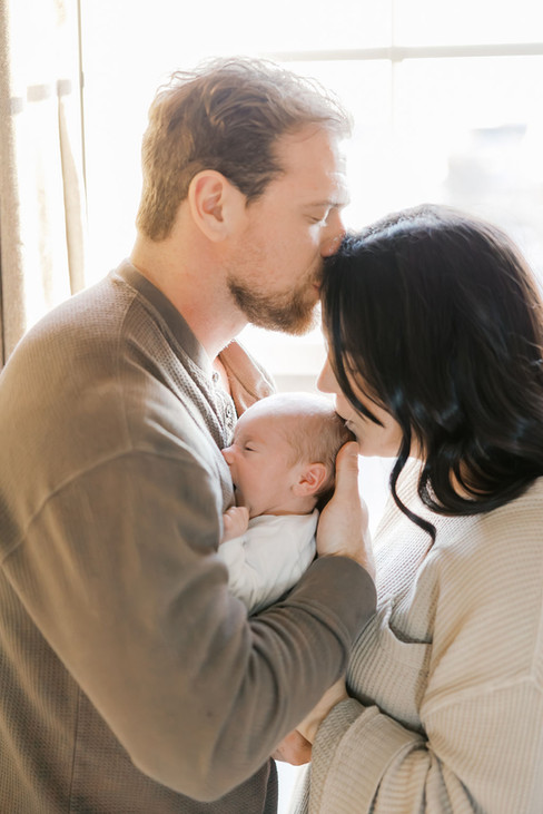 Parents kissing their newborn baby during an intimate lifestyle newborn photography session in Richmond
