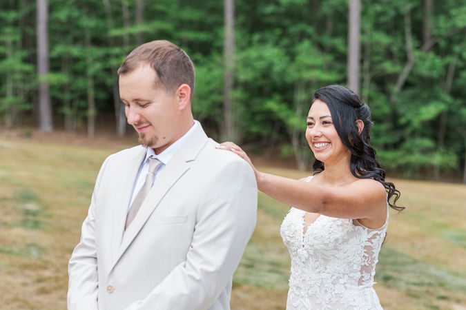 18. Bride gently tapping the groom’s shoulder, both smiling with excitement during their first look.