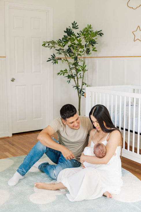 15. Father and mother sitting together holding newborn baby on floor