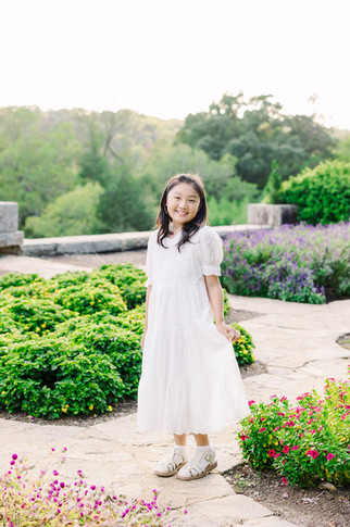 Individual portrait of a girl standing on the garden path at Maymont, surrounded by greenery and flowers.