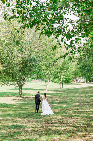 Bride and groom holding hands in an open park with lush greenery in Richmond, VA at Maymont Park