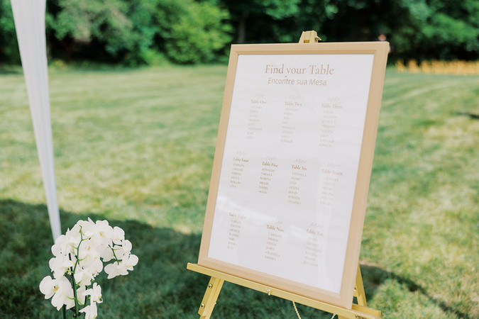 3. Close-up of wedding seating chart sign with white floral details for Barbara and Gustavo’s backyard wedding