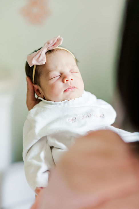1️⃣8️⃣ Close-up portrait of sleeping newborn baby girl with pink bow.