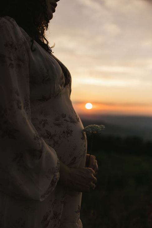 9. Detail shot of pregnant belly in floral dress during golden sunset maternity session