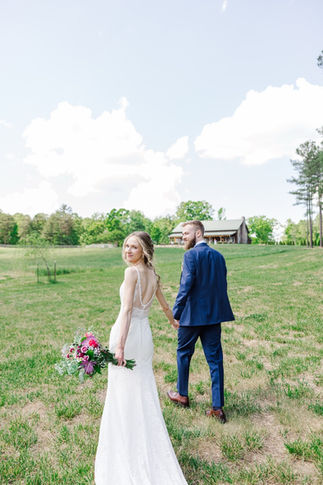 1. Bride and groom walking hand in hand across Virginia field