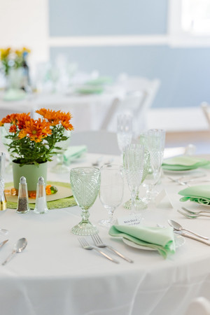 Close-up of a wedding table setting with intricate green glassware, fresh orange flowers, and fine dining details, richmond va