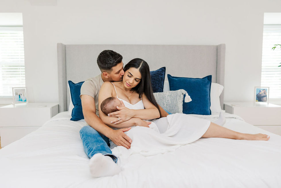 4. Father and mother on bed smiling at newborn baby