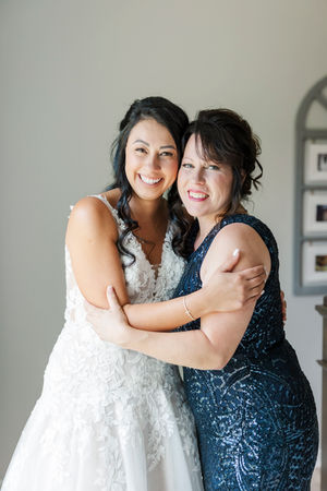 16. Bride sharing an affectionate embrace with her mother, both smiling warmly.