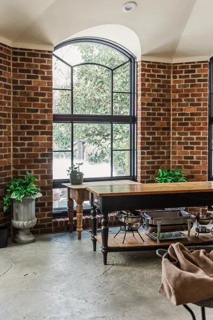 	16.	Rustic indoor dining space with exposed brick walls and large windows, adding charm to The Mill at Fine Creek.