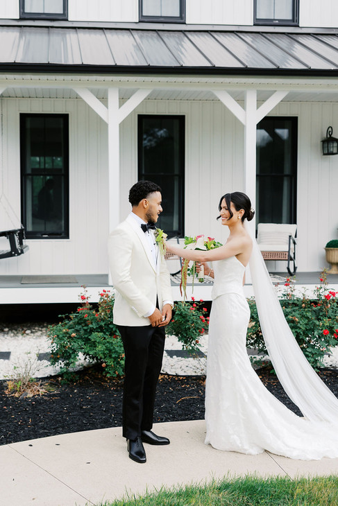 4. Groom standing by bright windows in a white tuxedo jacket before his private residence wedding ceremony