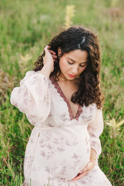 	15.	Expecting mother laying back in grass with serene smile, golden-hour maternity portrait