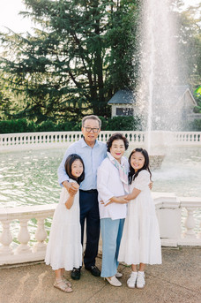 Grandparents surrounded by grandchildren dressed in white and blue tones at Maymont Park.