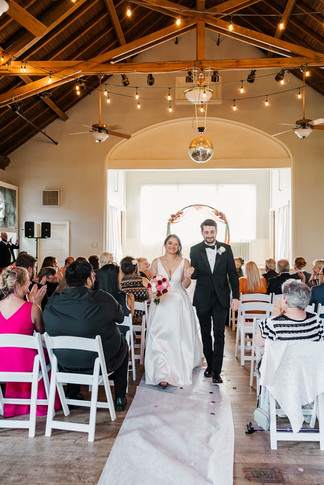 Bride and groom walking down the aisle together as newlyweds, with guests cheering at The Schoolhouse at Hawthorne in Richmond, VA.