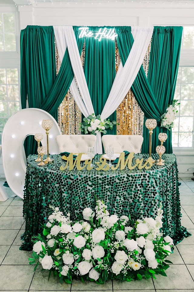 	14.	Champagne flutes with greenery backdrop and gold sequin tablecloth.