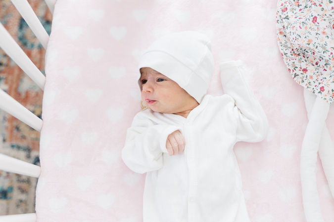 13. Baby in cozy white outfit on light pink blanket