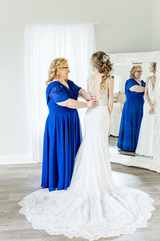 15. Mother of bride helping bride into gown in blue dress