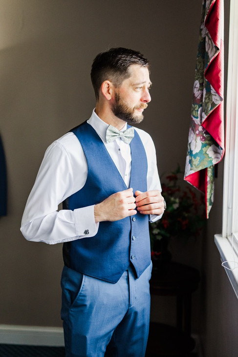 	9.	Groom adjusting vest while getting ready near window