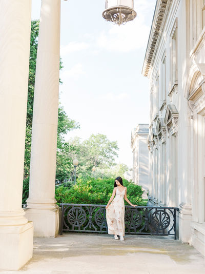 Senior standing under a grand porch, posing for her senior portraits with Richmond photographers.