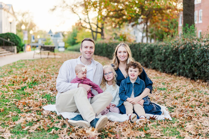 Family of five sitting together on a blanket in a field of autumn leaves at the VMFA in Richmond, Virginia.