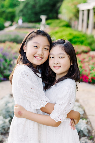 Teen sisters standing together in pastel dresses during a spring family session at Maymont, Richmond.