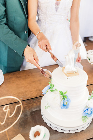 16. Bride and groom cutting their wedding cake decorated with blue and white flowers