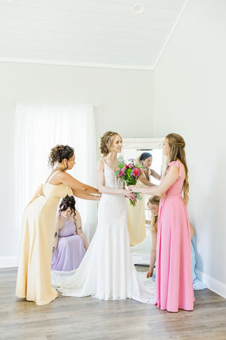 5. Bridesmaids helping bride with dress in pastel gowns