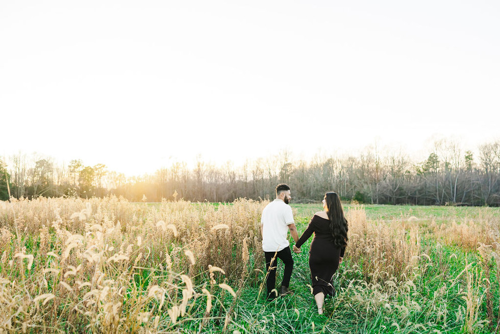 	10.	Wide shot of couple walking in field at golden hour during Richmond Battlefield maternity photos