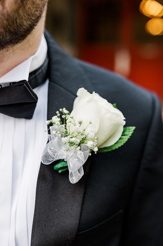 Detailed shot of the groom’s boutonniere pinned on his tuxedo.