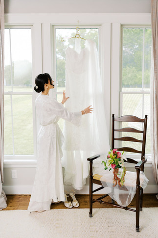 10. Bride closing the curtains while getting ready in a white robe before her spring wedding day