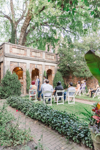 6. Side view of the ceremony setup with guests seated in a garden courtyard.
