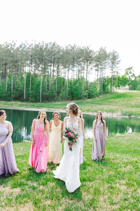 3. Bridesmaids walking by pond in pastel spring dresses