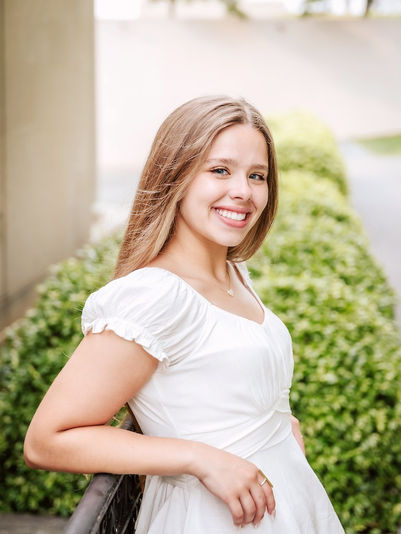 Senior girl in a white dress smiling during golden-hour senior portraits with Richmond photographer
