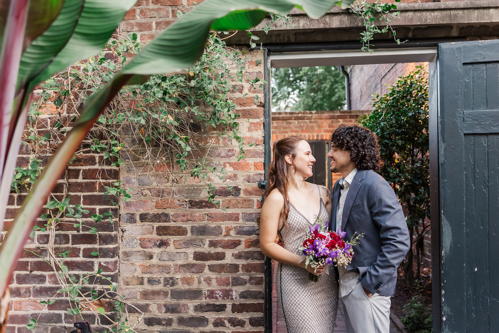 1. Bride and groom standing close together under a rustic garden arch, sharing an intimate moment.