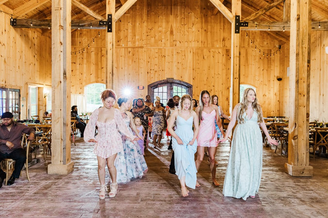 4. Guests dancing at wedding reception in wooden barn